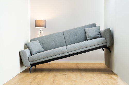 A couch that is wedge between two close walls.