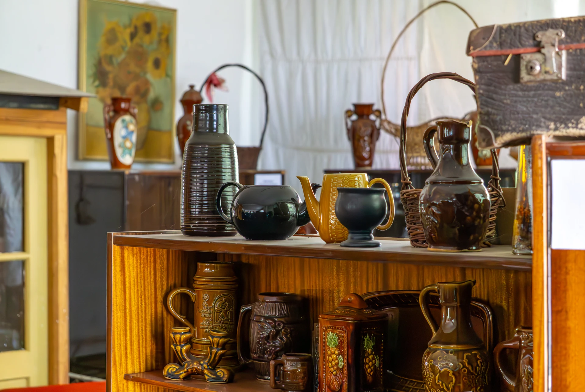 Wooden shelf with a collection of vintage ceramic jugs, mugs, and teapots